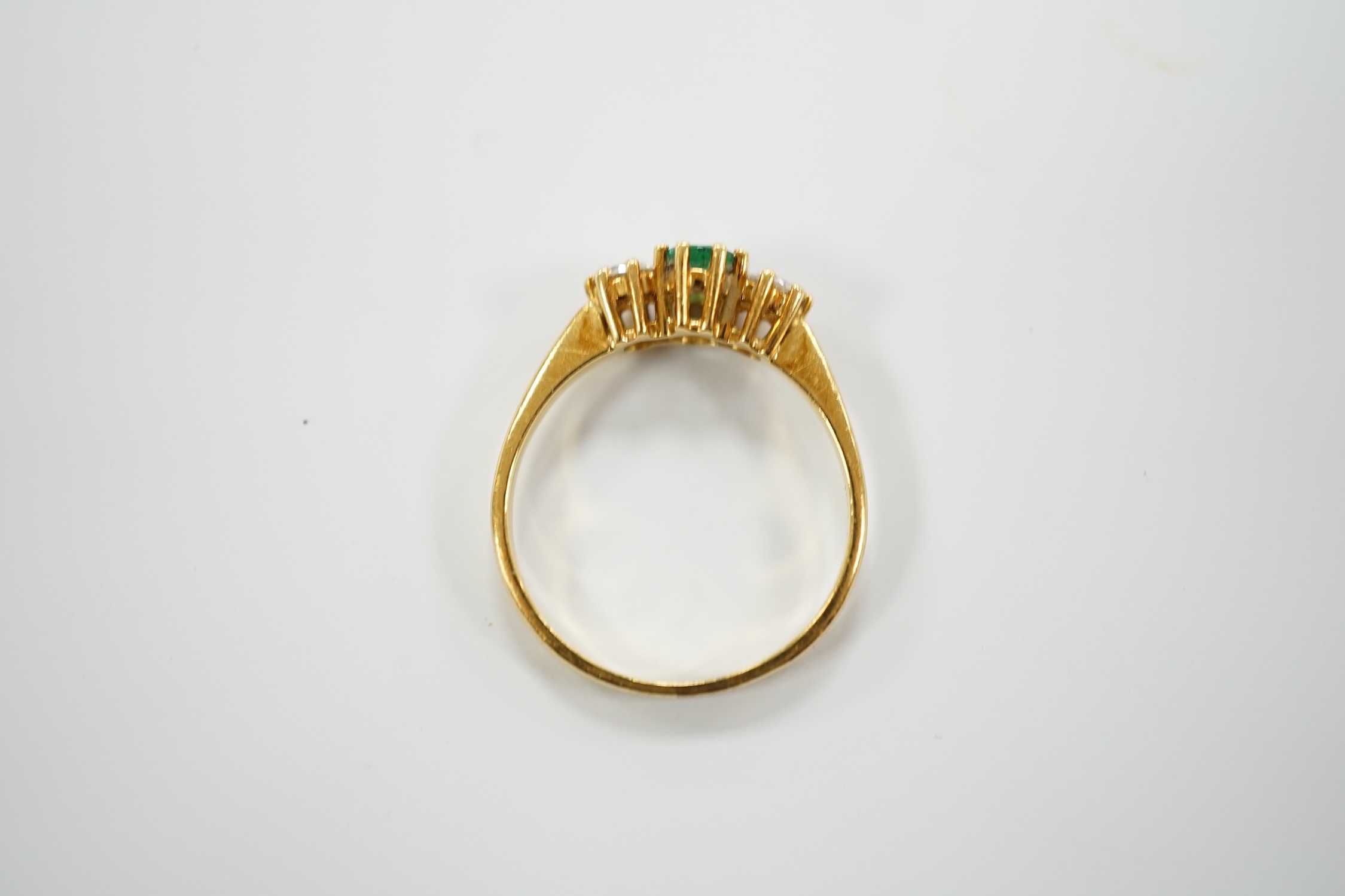 A modern 18ct gold, emerald and diamond set three stone ring, size P, gross weight 3.2 grams.